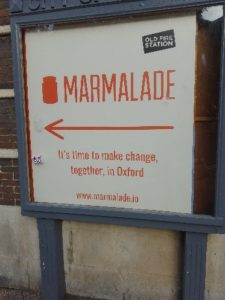 A sign on a building. Text on sign Marmalade. It's time to make change together, in Oxford. 