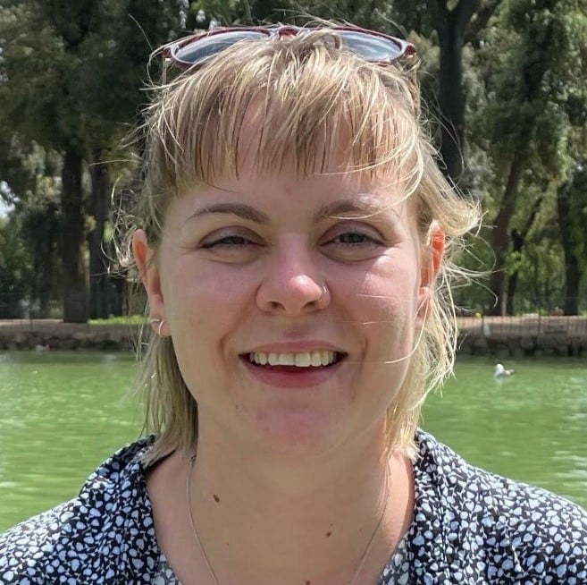 A woman smiling at a camera in the park