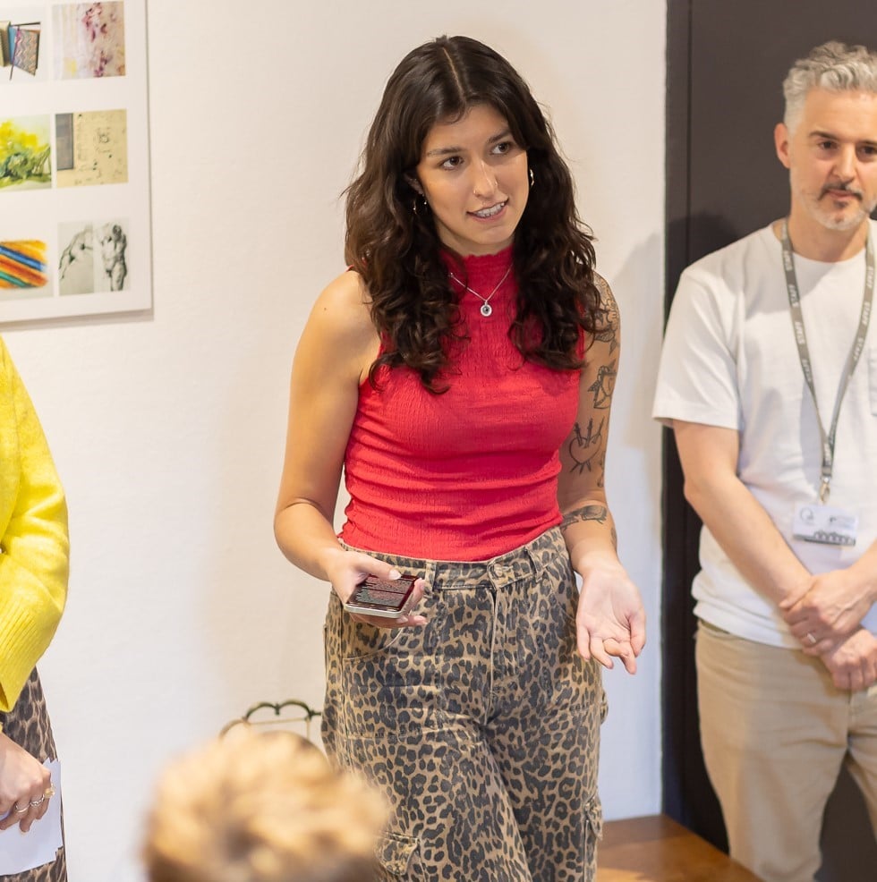 A woman with dark brown hair standing in a room with a few people